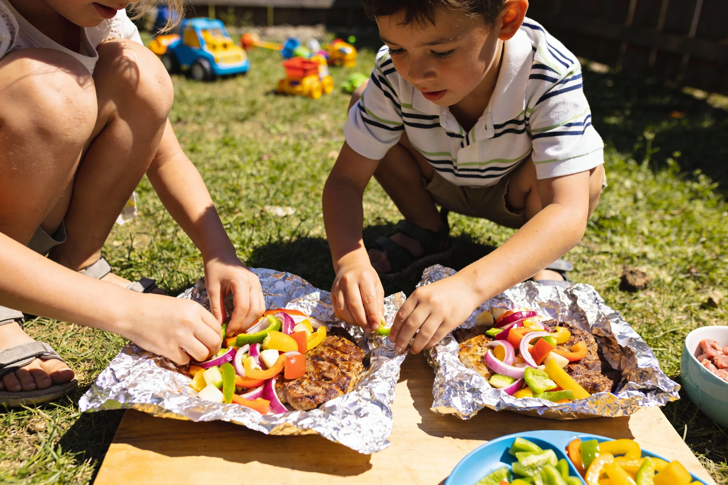 Kids assembling foil-packet meals in a backyard setting
